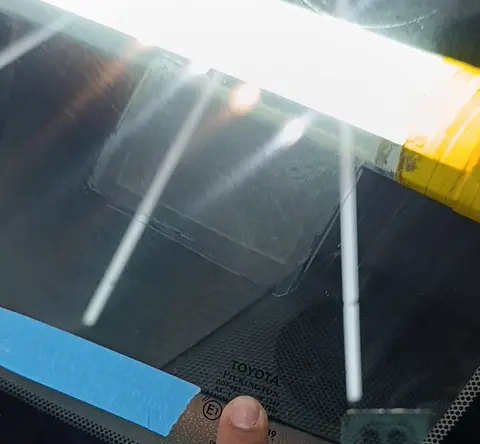 Dedo apontando a identificação de fábrica gravada no para-brisa original